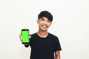 Asyalı bir adam yeşil ekranlı cep telefonunu gösteren siyah bir tişört giyiyor.