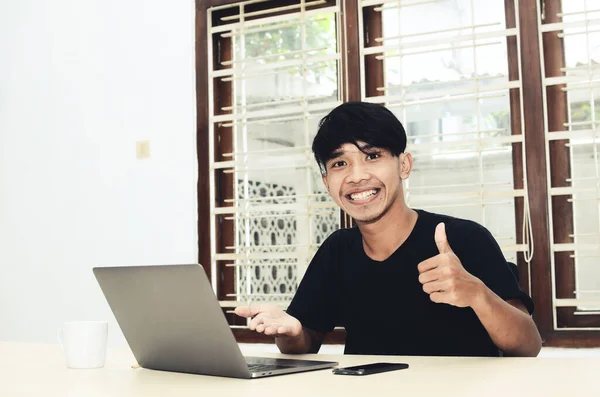 Asyalı adam dizüstü bilgisayarı işaret ederek oturuyordu.