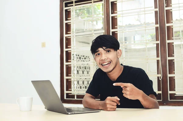 Asyalı adam dizüstü bilgisayarı işaret ederek oturuyordu.