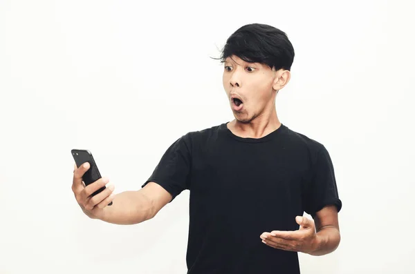 Ázsiai Férfi Alkalmi Fekete Pólóban Sokkoló Arckifejezéssel Telefonján — Stock Fotó