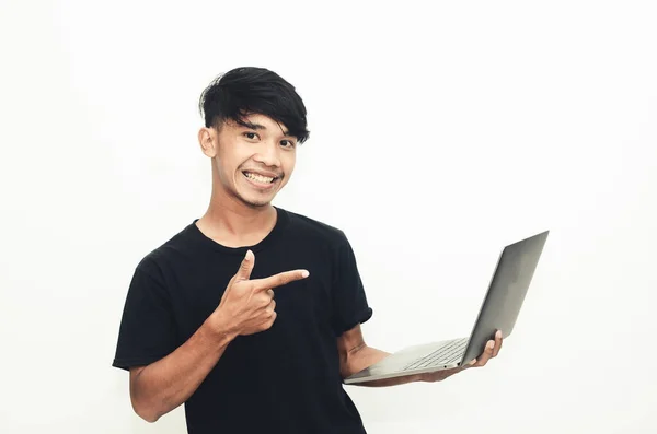 Sıradan Siyah Tişörtlü Asyalı Adam Dizüstü Bilgisayarı Işaret Ediyor — Stok fotoğraf