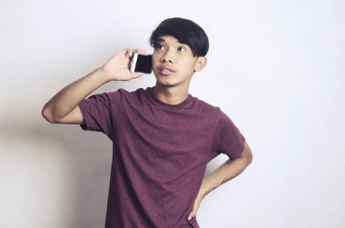 Genç Asyalı bir adam beyaz bir arka planda arama yapıyor.