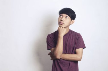 Beyaz bir arka planda kafası karışık ve düşünceli genç bir Asyalı.