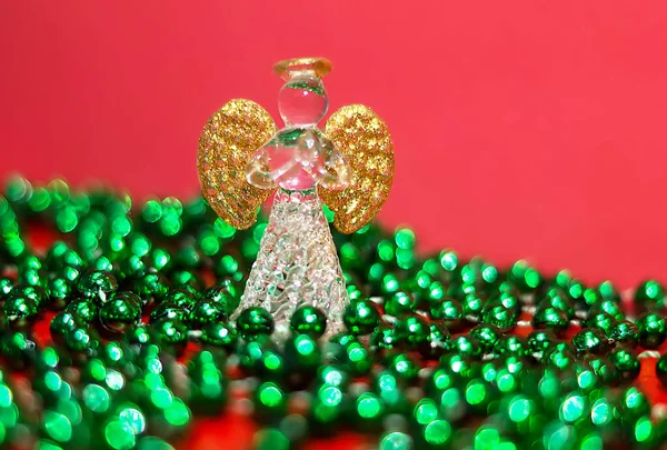 Crystal angel with Golden wings. Christmas decoration. Christmas background for greeting card. New year\'s picture. The angel stands in a blur of green beads. Copy the space for the text.