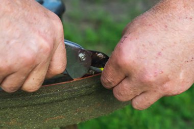 Bir işçinin kirli erkek elleri, yakın plan. Yenileme, çim biçme makinesinin kirli kafasının tamiri yüksek, yoğun bir şekilde büyümüş yeşil çim biçtikten sonra. Benzin bidonunu dolduruyorum..