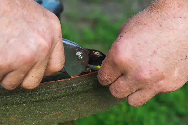 Bir işçinin kirli erkek elleri, yakın plan. Yenileme, çim biçme makinesinin kirli kafasının tamiri yüksek, yoğun bir şekilde büyümüş yeşil çim biçtikten sonra. Benzin bidonunu dolduruyorum..