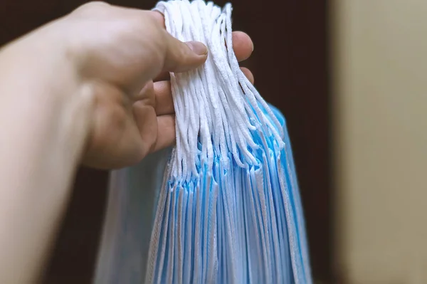 Bir kadının el ele tutuşması ve virüs hastalıklarına karşı bir yığın tek kullanımlık tıbbi maske vermesi. Bulaşıcı hastalıkların yayılmasını önlemek için bir kadının elindeki tıbbi maskelerin yakın plan görüntüleri.