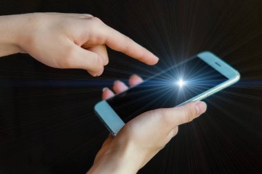 Kadının parmağı ekrandaki cep telefonunu ve siyah arka plandaki cep telefonunu gösteriyor. Genç bir kız ekranında güzel mavi bir ışık olan bir akıllı telefon tutuyor. Çevrimiçi iletişim,