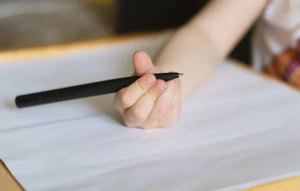 Рука Ребенка Держит Большую Черную Шариковую Ручку Рисует Белом Листе — стоковое фото
