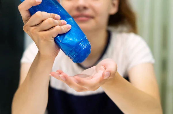 女性の手に子供の粘りのあるスライムを持つプラスチックボトル 10代の少女の手は 透明な瓶から青いスライムを手の手のひらに注ぐ ゲーム エンターテイメントのコンセプト — ストック写真