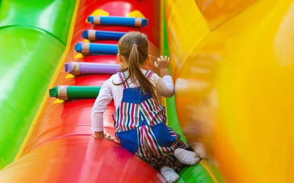 喜びの小さな女の子は 高インフレータブルスライドで楽しんでいます 小さな子供がお祝いの日にインフレータブルトランポリンで遊んでいます 幸せな 楽しい子供時代 子供向けのエンターテイメント 子供向けゲーム ストックフォト