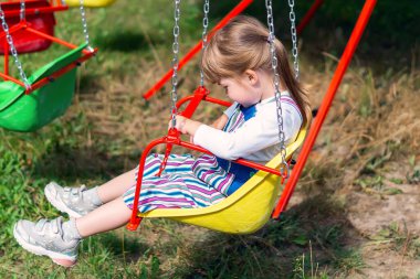 Küçük bir kız zincirli bir atlıkarıncanın sandalyesinde sessizce oturuyor. Küçük tatlı bir kız salıncakta sallanıyor. Bebek lunaparkta bir salıncakta dönüyor. Tasasız çocukluk ve mutluluk