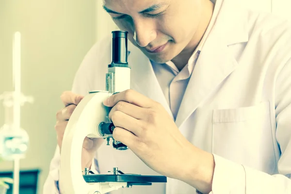 Asyalı bilim adamları veya kimyagerler mikroskop kullanıyorlar. Bilimsel deneyde Tıbbi farmasötik araştırma konsepti DNA yapısı, yenilik ve teknoloji