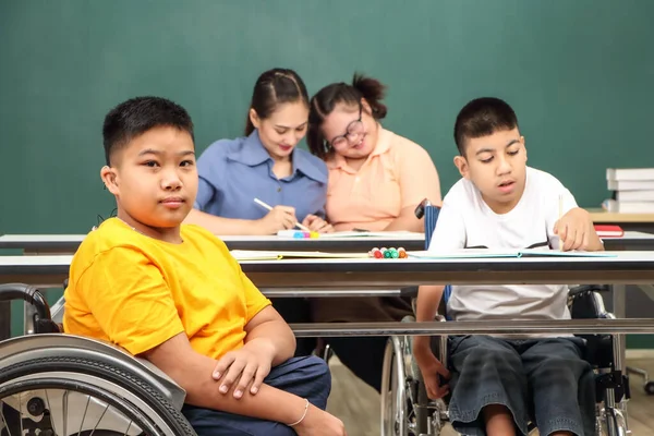 Asian disabled children Or, an autistic child learns to read, write, and train their hand and finger muscles with a teacher at their classroom desk. Concentrate and smile Happy disability kid concept