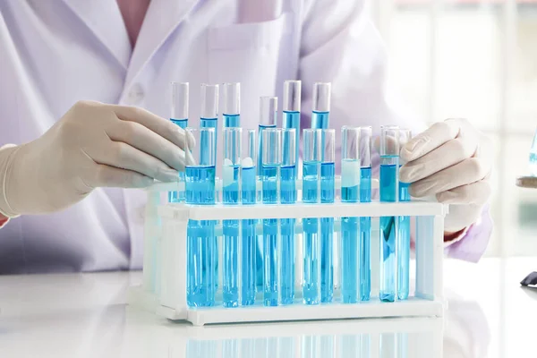 Asyalı bir bilim adamı ya da kimyager laboratuvara mavi sıvı bir kimyasal bırakıyor. Sağlık, eczane ve tıp alanlarındaki araştırma kavramları. DNA ve molekülleri tüp içinde ayırmak için sıvı analizi.