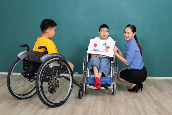 A group of young girls with disabilities and autism is training their hand and finger muscles by drawing and painting with water. With the help of teachers Happy and focused in the classroom