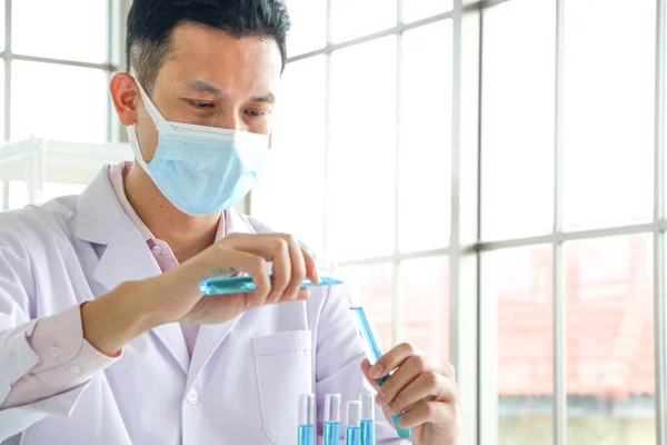 一位亚洲科学家或化学家把一种蓝色液体化学品扔在实验室里 制药和医学的研究概念 Dna和分子体外分离的液体分析 — 图库照片