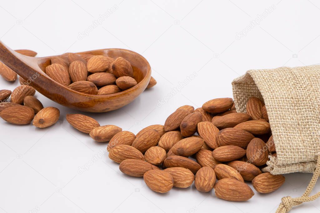 Almonds in a cloth bag and a wooden spoon separated the leg background Organic food concept. Contains vitamins and minerals. Helps to neutralize free radicals. Nourish the castle and brain system