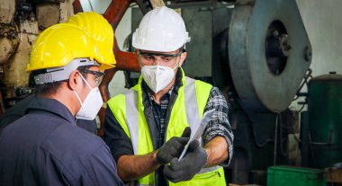 Üniforma ve gözlük takan profesyonel Asyalı erkek mühendislerden oluşan bir ekip, makine bakım ve kurulumunu analiz etmek için bir tablet kullanıyor. Endüstriyel fabrikalarda mühendislik kavramları