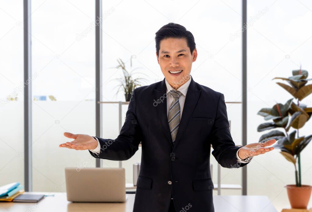 Portrait of an Asian adult businessman in a suit And stood looking at the camera, smiling happily He relaxed, confident and Are satisfied and diverse Work in the office Develop new business projects
