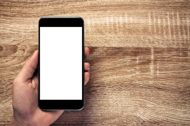 Ahşap Masa 'da güzel desenli beyaz ekranlı akıllı telefonu tutan ve içerik eklemek için alan kopyalayan adam. Akıllı telefon konsepti ve yaşam tarzı. kırpma yolunu içerir