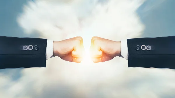 Fight, Interruption and coping with economic conflicts, competition with business competitors during the covid-19. Two fists hitting with sunlight effect on sky background. Concept of struggle.