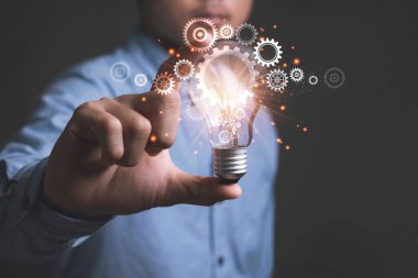 Genç Asyalı iş adamı ampulleri tutuyor. Fikir kavramı ve Beyin Fırtınası yaratıcılığı, yeni fikirler sunarak fikir üretme Büyük ilham ve yenilik yeni başlangıç.