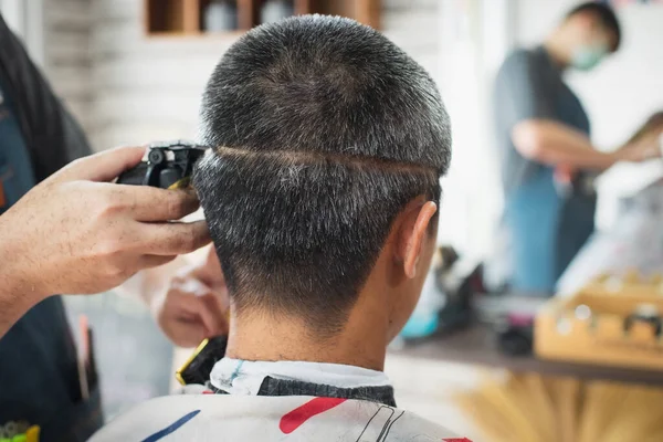 Asyalı Genç Adam Berber Dükkanında Berber Tarafından Elektrikli Makasla Saçlarını — Stok fotoğraf