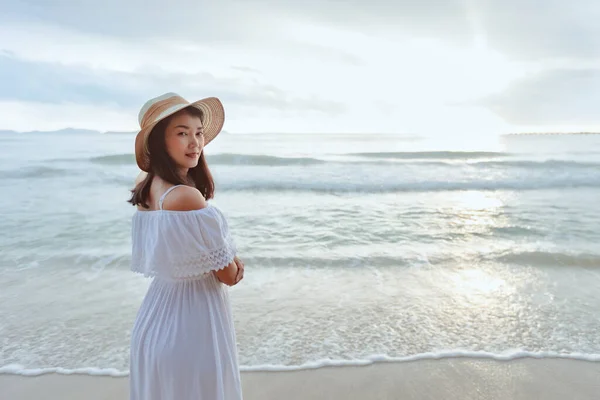 スタイリッシュな帽子と服を身に着けて海を眺め ビーチで美しい夕日を楽しむアジアの女性 夏休みと旅行のコンセプト — ストック写真