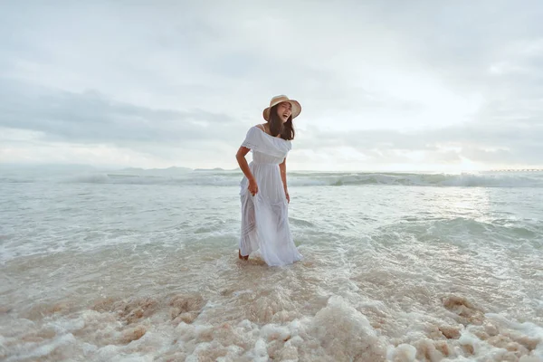 海の中で幸せを感じながら水遊びをしながら 夕日の時間に美しい自然を楽しみながら スタイリッシュな帽子と服を身に着けているアジアの女性 夏休みと旅行のコンセプト — ストック写真
