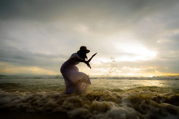 海辺の波で海で水遊びをしながら夕日の時間に美しい自然を楽しむアジアの女性のシルエット 夏休みと旅行のコンセプト — ストック写真