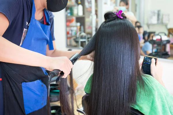 Genç Asyalı Kadın Kuaförden Düz Saç Düzleştirici Alırken Akıllı Telefon — Stok fotoğraf