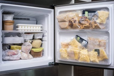 freezer of modern frigerator full with frozen food products in quarantine or work from home period during coronavirus pandemic clipart