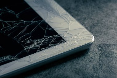 cracked or broken screen of smartphone or tablet on grunge background
