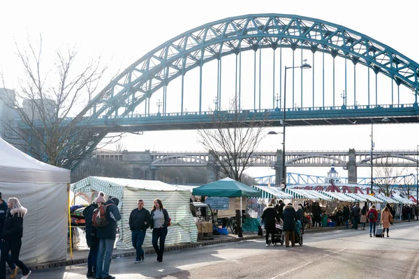 Tyne England 'daki Newcastle: 10.02.2019: Quayside Pazar Pazarı boyunca yürüyen insanlar. Arka planda Tyne Köprüsü olan tezgahların görüntüsü