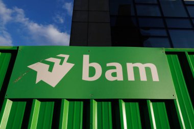 Bristol UK: 28 Temmuz 2025: Bristol 'deki BAM İnşaat alanı, yukarıda açık mavi bir gökyüzü ve uzakta bir vinç ile. Canlı yeşil kap BAM markasını gösterir