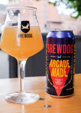Bristol UK: 28 Temmuz 2025: Bristol Brewdog 'da alkolsüz bir içecek ve güneşli bir havada ahşap masa üzerinde bira keyfi yapmak