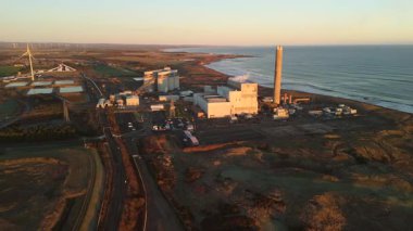 Lynemouth Northumberland: 31 Aralık 2025: Lynemouth Enerji İstasyonu kış sabahı insansız hava aracı görüntülerinin üzerinde duruyor. Güneş doğuyor, Endüstri binalarına ve yakındaki kıyı şeridine ışık tutuyor.