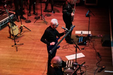 Newcastle on Tyne: 18 Aralık 2025: The Trevor Horn Band O2 City Hall Newcastle 'da konser verdi. Trevor Horn, grubu Newcastle City Hall ile birlikte bir bas gitar tutuyor.