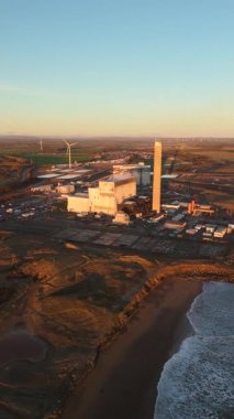 Lynemouth Northumberland: 31 Aralık 2025: Lynemouth Enerji İstasyonu kış sabahı insansız hava aracı görüntülerinin üzerinde duruyor. Güneş doğuyor, Endüstri binalarına ve yakındaki kıyı şeridine ışık tutuyor.