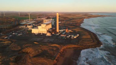 Lynemouth Northumberland: 31 Aralık 2025: Lynemouth Enerji İstasyonu kış sabahı insansız hava aracı görüntülerinin üzerinde duruyor. Güneş doğuyor, Endüstri binalarına ve yakındaki kıyı şeridine ışık tutuyor.