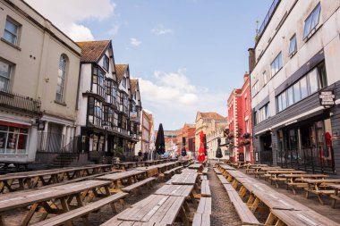 Bristol İngiltere: 28 Haziran 2025: Yoğun bir cadde boyunca Bristol barları ve barları oturma yerleri ve açık mavi gökyüzü (sabahleyin hiç kimse)