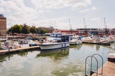 Bristol UK: 28 Temmuz 2025: Güneşli bir günde Bristol Limanı 'nda arkaplanda binalar ve su bulunan tekneler yanaştı