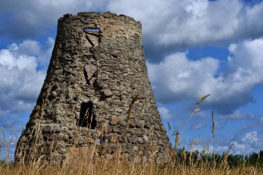 Güneşli bir yaz gününde, bulutlu mavi gökyüzünün altında, eski bir yel değirmeninin taş kulesi, Kohtla-Jarve, Estonya.