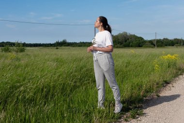 Orta yaşlı bir kadının, toprak bir yolun kenarında dikilip gökyüzüne bakarken tüm vücudu samimi bir portresi. İmaj, iyimserliği, özgürlüğü ve kırsal kesimdeki doğa ile olan bağlantıyı aktarıyor..