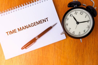 Çalar saat konsepti ve ahşap arka planda sabahları ışık sızıntısı olan bir defter..