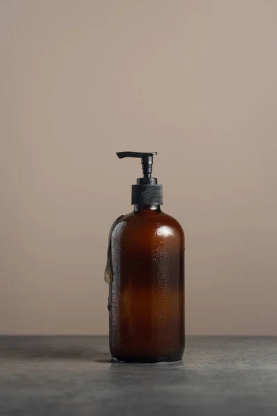친환경적 인 호박 유리 비누 배급사는 어두운 대리석 배경에 식기세척기나 바디 워시를 채워 넣은 펌프 병을 사용 한다. — 스톡 사진