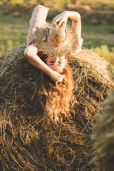 Schöne Frau auf einem Heuhaufen — Stockfoto