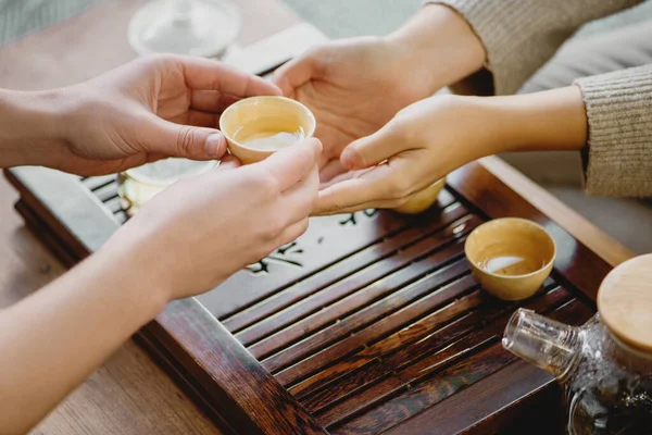 Mannelijke handen geven kleine porseleinen beker met thee aan vrouw tijdens een thee ceremonie. — Stockfoto