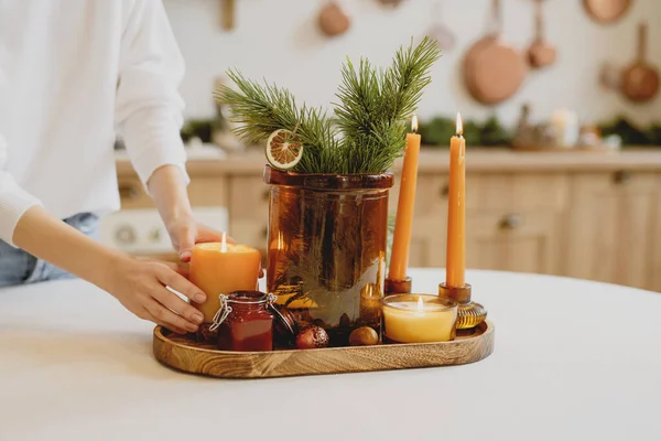 stock image A woman decorates a Christmas table arrangement with candles.